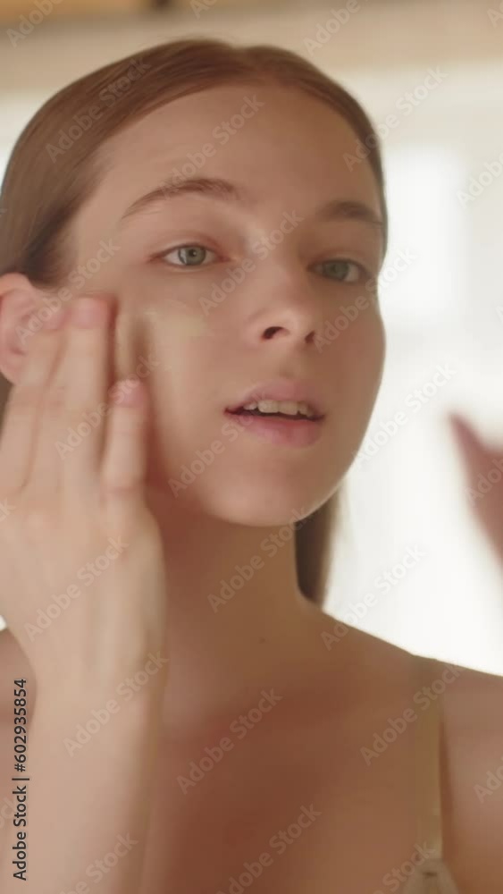 Rear view calm beautiful young lady applying face foundation Rear view calm beautiful young lady applying face foundation