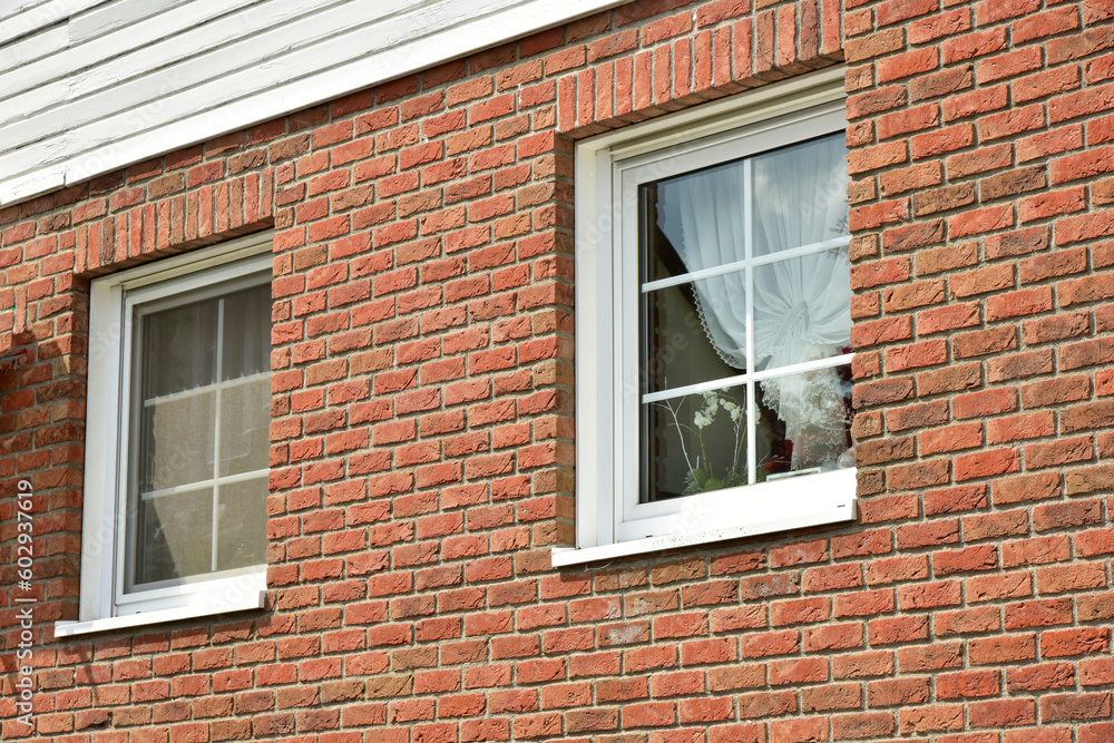 Fassade eines modernen neu gebauten Fertighauses mit Vorsatz-Verklinkerung und passenden Fenstern mit Fensterkreuzen im Landhaus-Stil