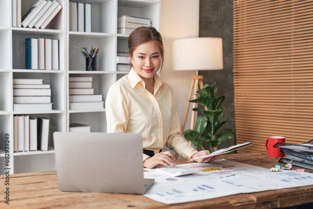 Businesswoman sits at work with laptop and computer and analyzes corporate and tax activities at office Businesswoman sits at work with laptop and computer and analyzes corporate and tax activities at office