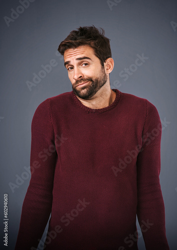 Confused, shrug and portrait of man in studio unsure against a grey background space. Doubt, face and shrugging male with dont know expression, puzzled and pensive with person with question isolated photo
