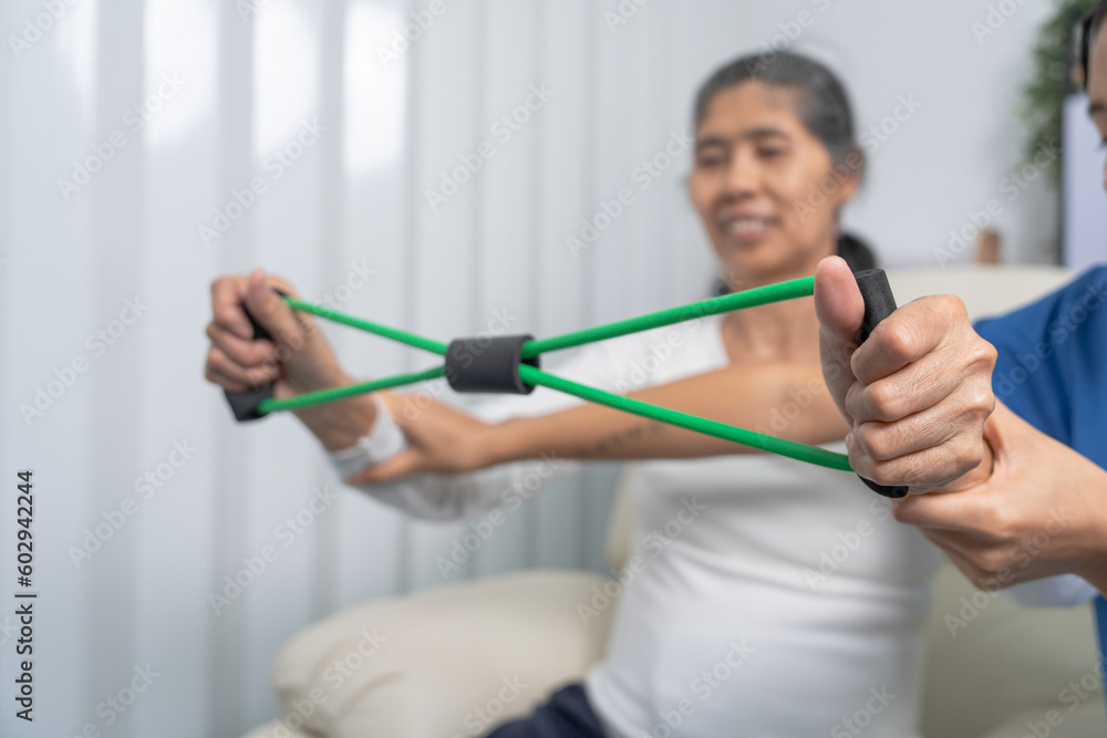 Concept of World Confederation for Physical Therapy. young physiotherapist caregiver helping mature elderly woman training with elastics in rehabilitation center, muscle weakness Concept of World Confederation for Physical Therapy. young physiotherapist caregiver helping mature elderly woman training with elastics in rehabilitation center, muscle weakness