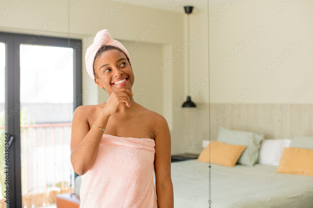 black afro woman smiling with a happy, confident expression with hand on chin. bathrobe concept black afro woman smiling with a happy, confident expression with hand on chin. bathrobe concept