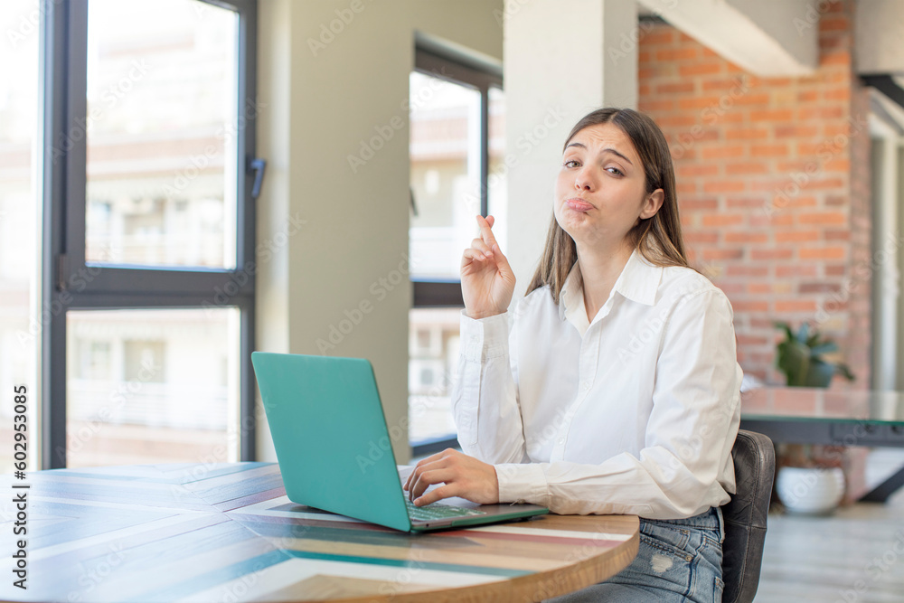 young pretty woman crossing fingers and hoping for good luck. working with a laptop young pretty woman crossing fingers and hoping for good luck. working with a laptop
