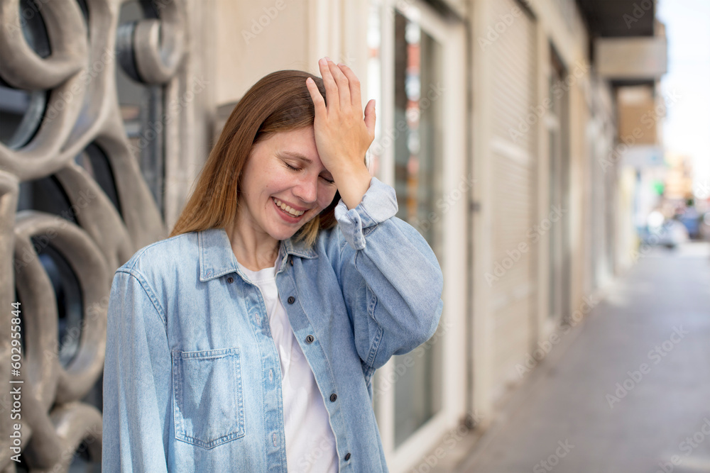 Fototapeta premium pretty young woman laughing and slapping forehead like saying d’oh! I forgot or that was a stupid mistake