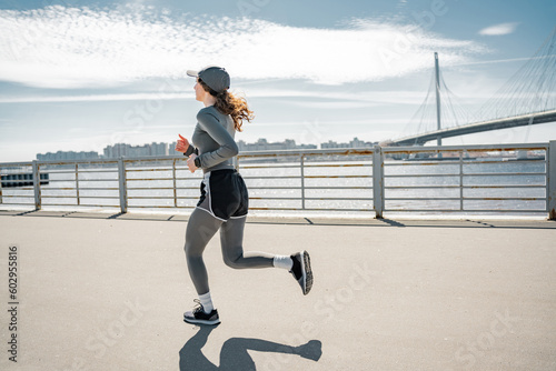 Rear view full-height fitness for a healthy lifestyle, jogging fast during the day in sports clothes training in the city a strong woman , cardio load on the body.