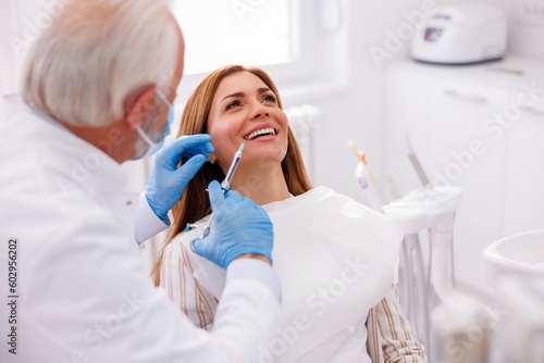 Dentist applying local anesthetic to female patient