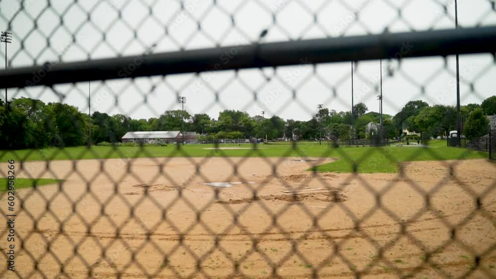 View of a baseball diamond through a fence on an overcast day in Boston. View of a baseball diamond through a fence on an overcast day in Boston.