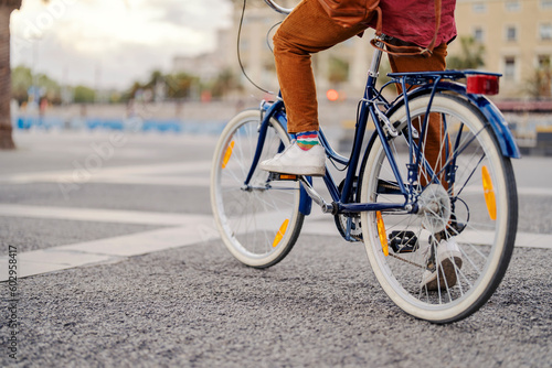 Cropped picture of a male's legs riding a bike on a street.