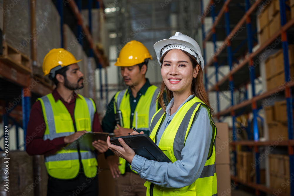 Warehouse employees reading a clipboard ann checking packages on shelf in a large logistics centre. Warehouse employees reading a clipboard ann checking packages on shelf in a large logistics centre.