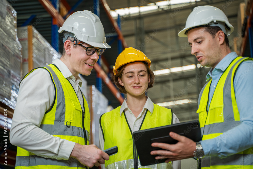 Warehouse employees reading a clipboard ann checking packages on shelf in a large logistics centre. Warehouse employees reading a clipboard ann checking packages on shelf in a large logistics centre.