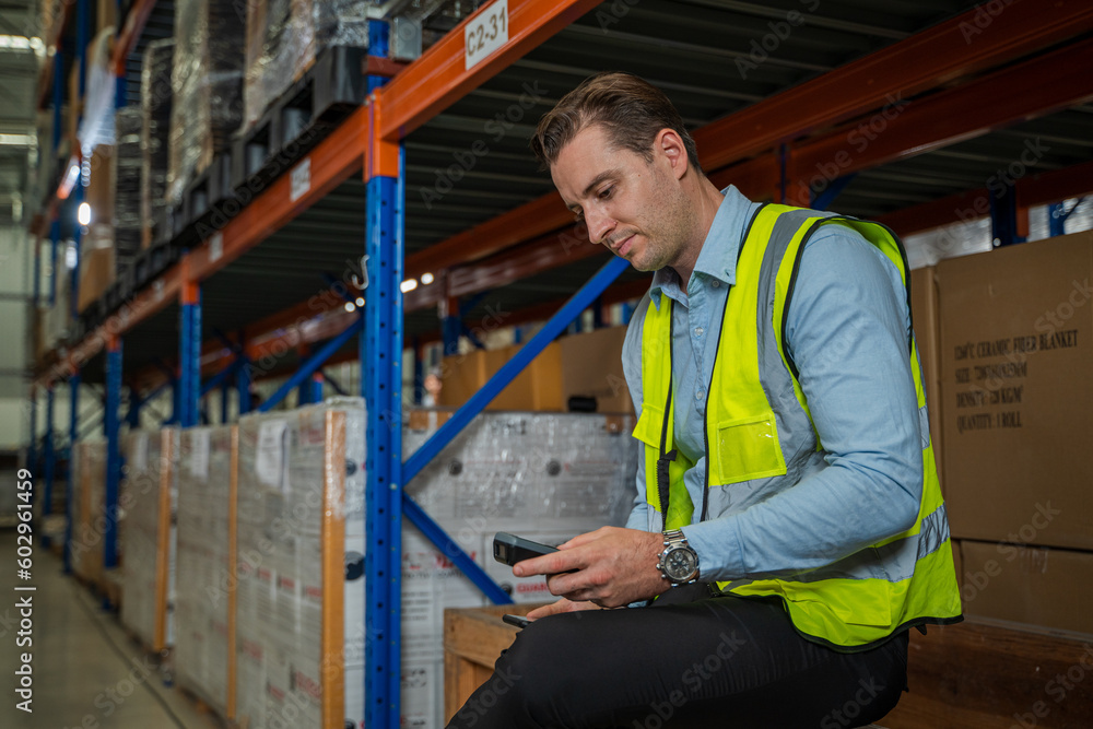 Warehouse worker uses digital tablet for checking stock in a large distribution warehouse.