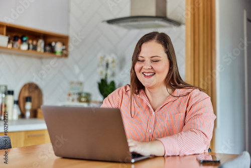 A smiling curvy businesswoman having an online video call over the laptop.