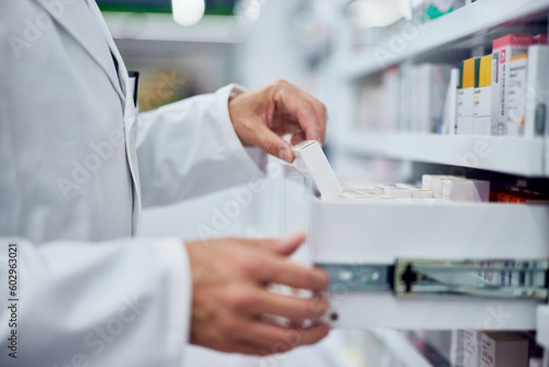 Side view of an pharmacist  taking a box of medicine  dressed in a white uniform.