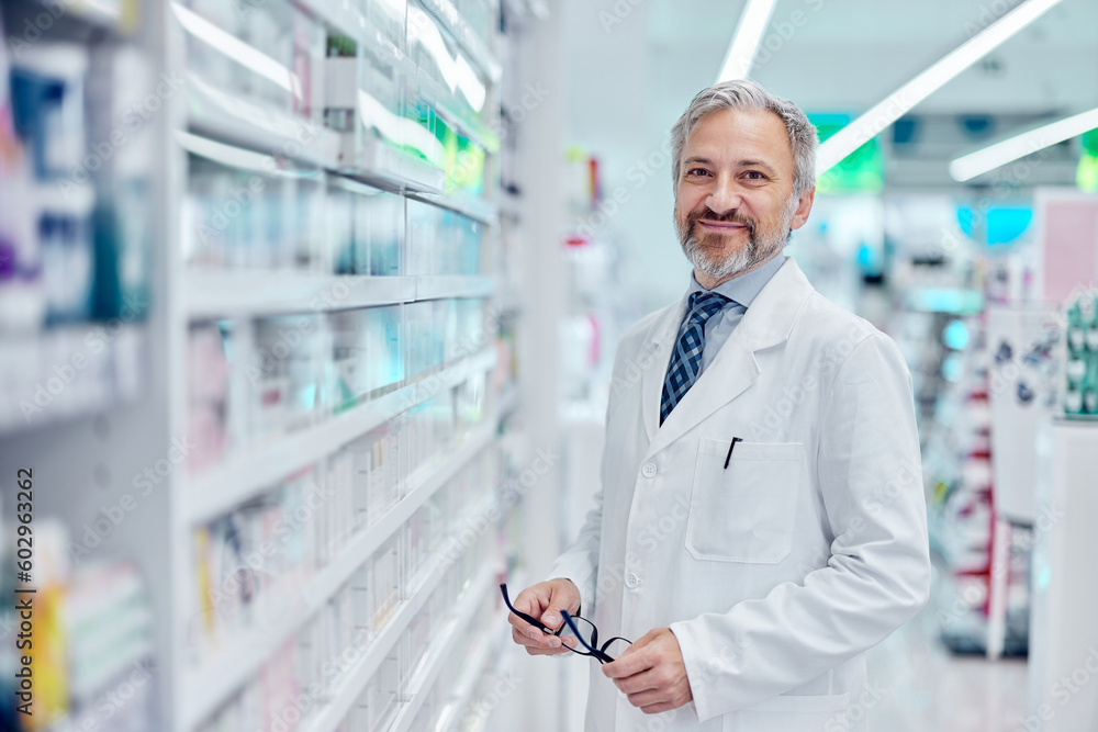 Portrait of a man working as a pharmacist, at the pharmacy, holding glasses, smiling for the camera. Portrait of a man working as a pharmacist, at the pharmacy, holding glasses, smiling for the camera.