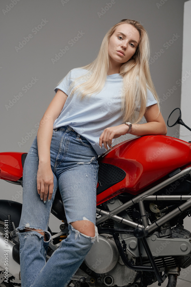 Shot of dressed in casual clothing woman motorcyclist and her powerful motorbike. Shot of dressed in casual clothing woman motorcyclist and her powerful motorbike.