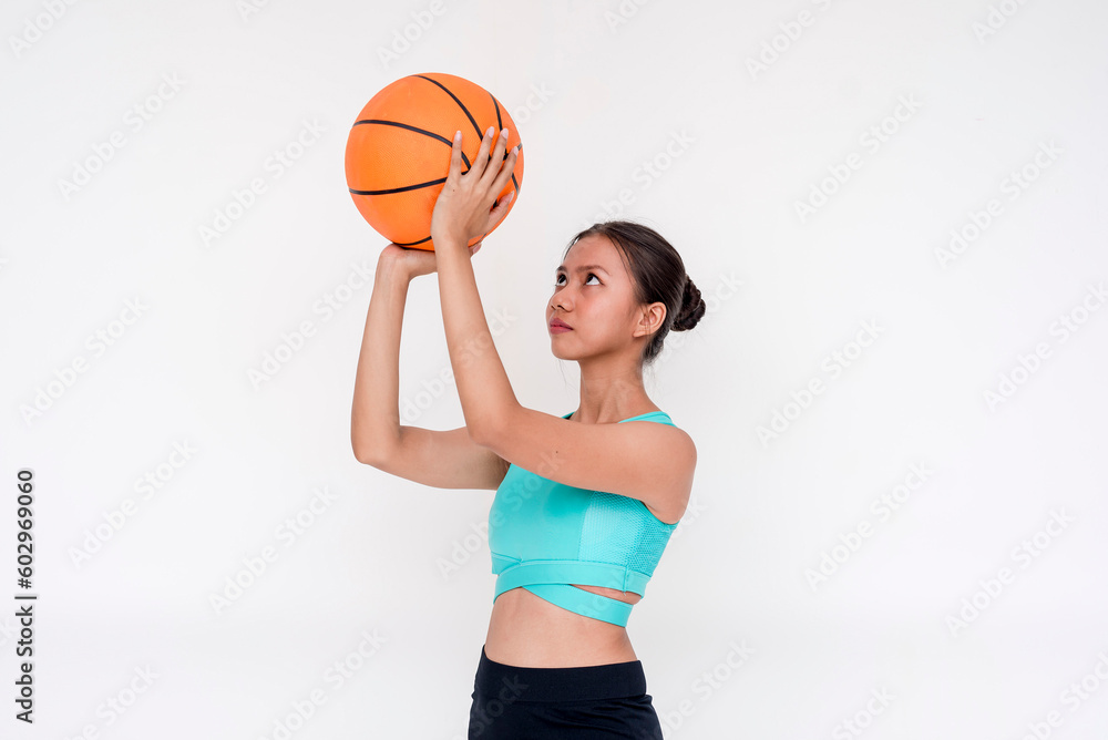 A focused and determined young woman tossing the basketball upwards. Isolated on a white background. A focused and determined young woman tossing the basketball upwards. Isolated on a white background.