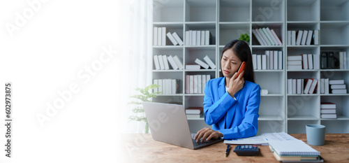 Busy businesswoman wearing a suit busy with work workaholic while sitting at work clear paperworks with documents and talk on the phone on your smartphone hear the hustle and bustle, busy concepts.