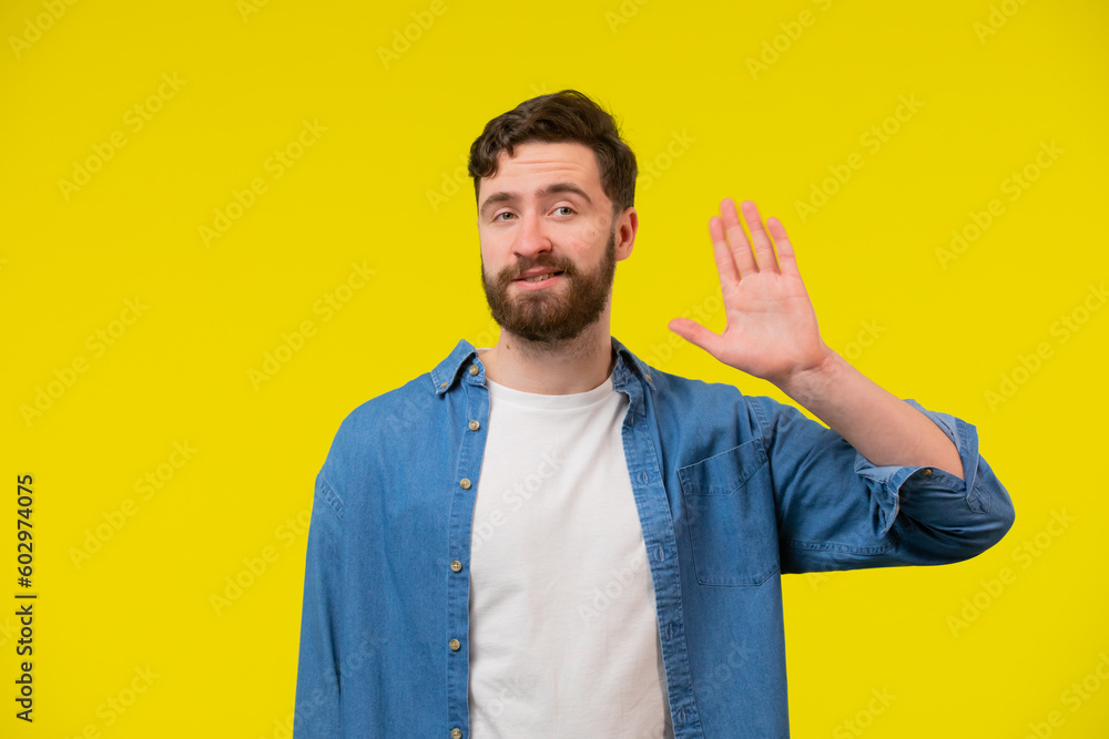 Hello Hi Young cheerful handsome bearded man greeting with open hand, enjoying communication, isolated on yellow background. close up portrait, body language. Hello Hi Young cheerful handsome bearded man greeting with open hand, enjoying communication, isolated on yellow background. close up portrait, body language.
