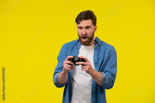 Close up photo of nervous scary fan of video games, he is holding a console, isolated on bright yellow background, copyspace © kinomaster