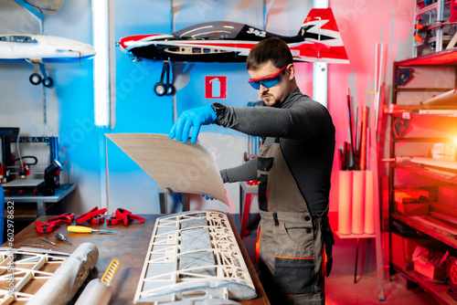 Male engineer or technician working on drone details in lab. Aircraft capable of GPS surveillance. Carbone wing. photo