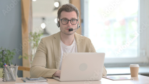 Young Businessman with Headset Looking toward Camera in Call Center
