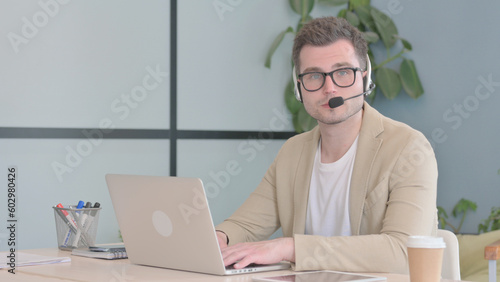 Young Businessman with Headset Looking toward Camera in Call Center