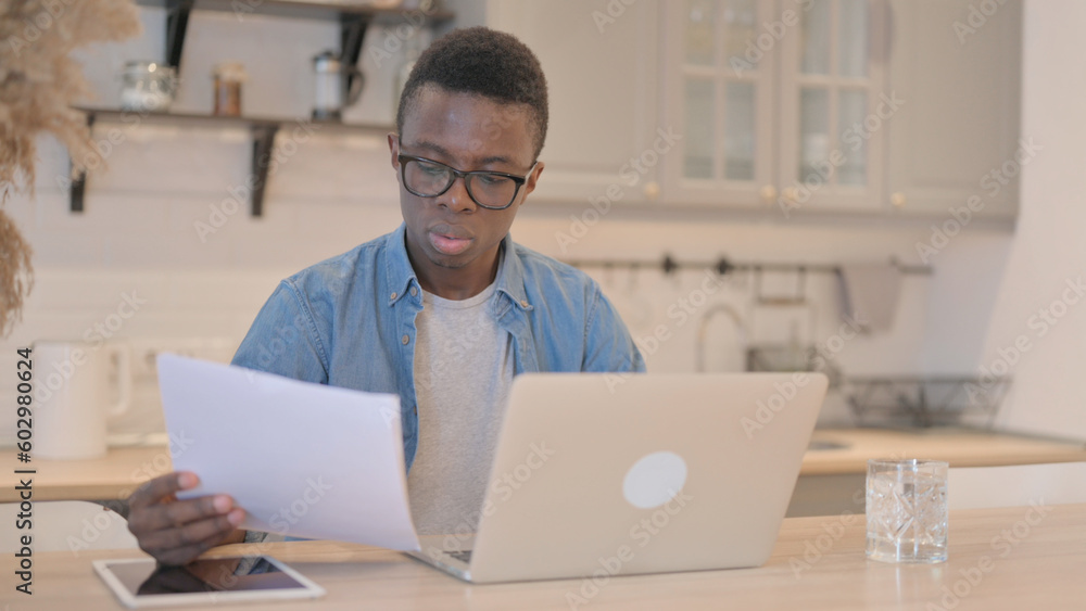 Reading Document by Young African Man and Working on Laptop Reading Document by Young African Man and Working on Laptop