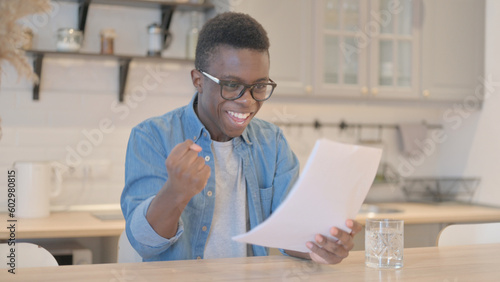 Young African Man Celebrating while Reacting to Business Report,