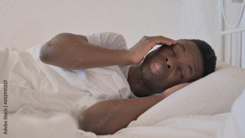 Young African Man with Headache Lying in Bed on Side Young African Man with Headache Lying in Bed on Side
