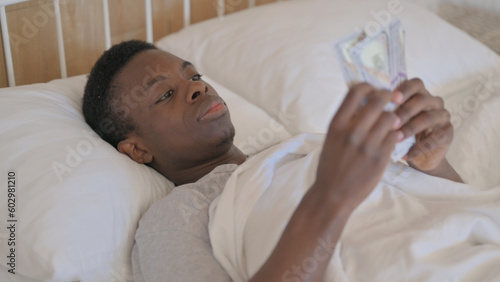 Young African Man Counting Money in Bed