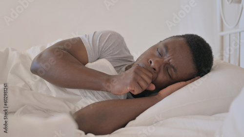 Sick Young African Man Coughing while Lying in Bed on Side