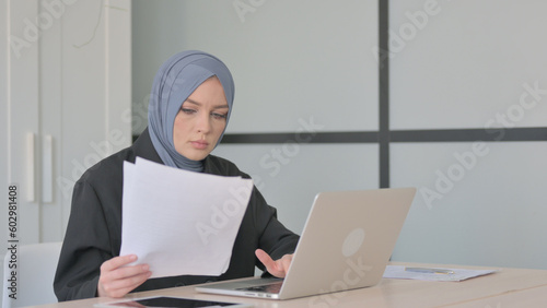 Reading Document by Muslim Businesswoman and Working on Laptop