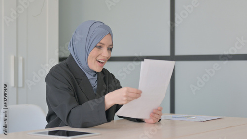 Muslim Businesswoman Celebrating while Reacting to Business Report, © stockbakers