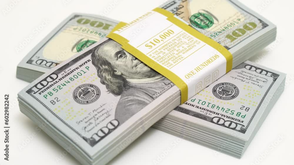 stack of bank bundles with US dollars on a white background. Close-up shot of new, freshly printed hundred-dollar bills rotating on a table. cash flow, business investment, or big money concepts. stack of bank bundles with US dollars on a white background. Close-up shot of new, freshly printed hundred-dollar bills rotating on a table. cash flow, business investment, or big money concepts.