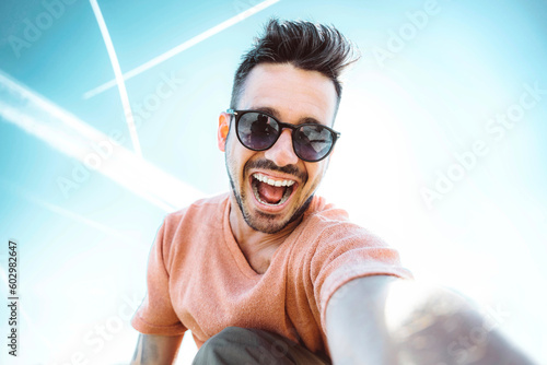 Handsome young man taking selfie with smart mobile phone outside - Cheerful guy smiling at camera - Trendy technology and people concept