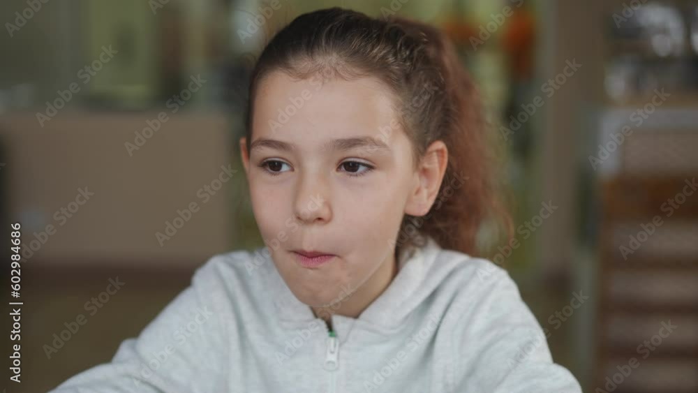 Smiling happy girl eating delicious dumpling in slow motion looking away. Brunette Caucasian kid with brown eyes enjoying tasty food in cafe indoors Smiling happy girl eating delicious dumpling in slow motion looking away. Brunette Caucasian kid with brown eyes enjoying tasty food in cafe indoors