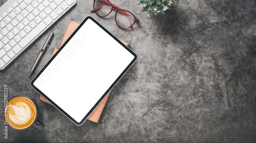 Dark office desk workplace with blank screen tablet, keyboard, eyeglass, notebook, pen and cup of coffee, Top view flat lay with copy space.