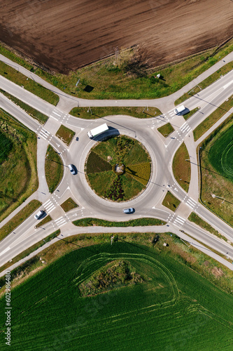 Roundabout intersection road traffic with many vehicles, aerial shot from drone pov