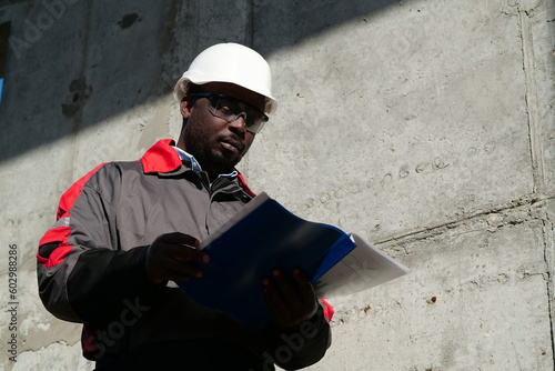 Vászonkép African american worker stands at construction site with work papers