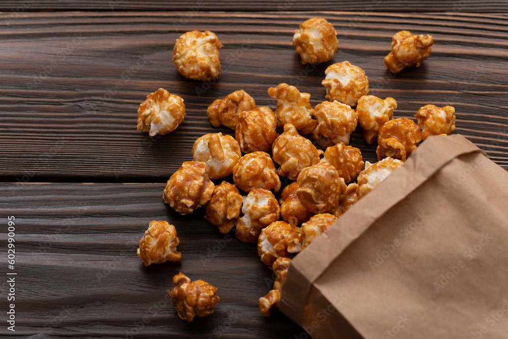 Caramelized popcorn in paper bag with copy space on wooden kitchen table flat lay