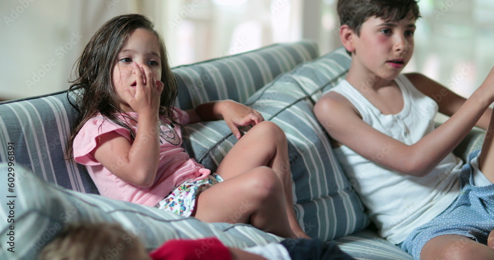 Candid children at home watching movie on couch Candid children at home watching movie on couch