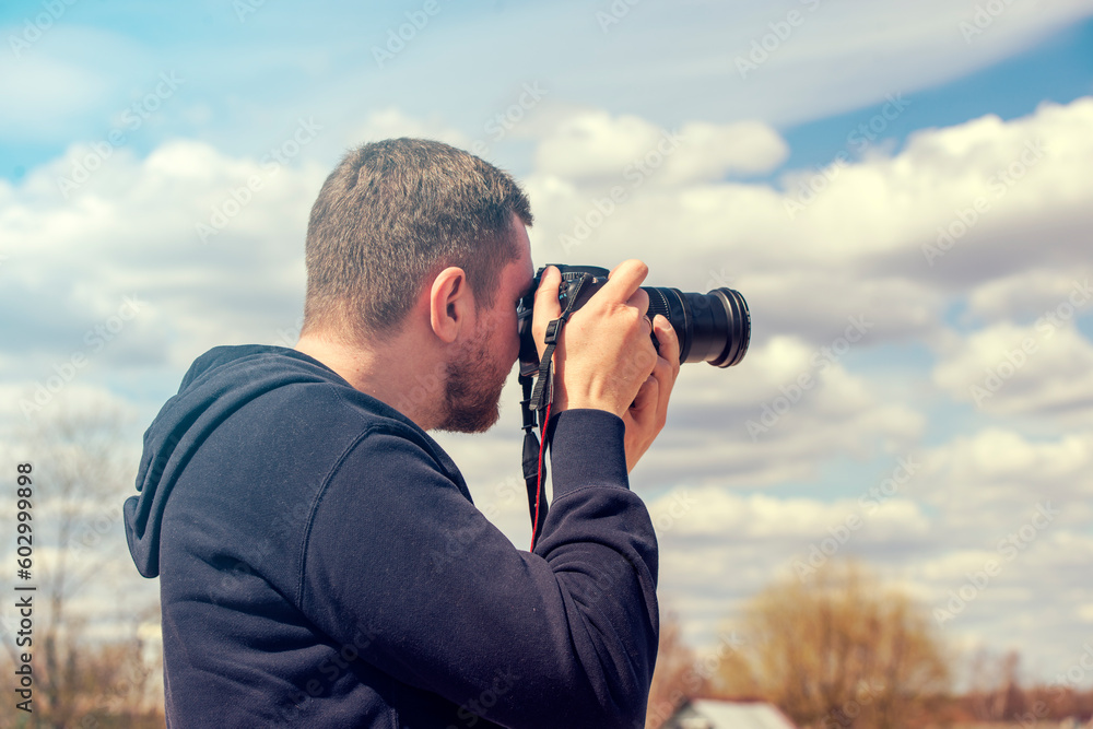Person taking picture by reflex camera. Man with black photo camera in warm summer day Person taking picture by reflex camera. Man with black photo camera in warm summer day