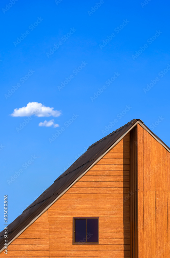 Obraz premium Glass attic window on wooden gable roof of vintage house against blue sky in minimal style and vertical frame