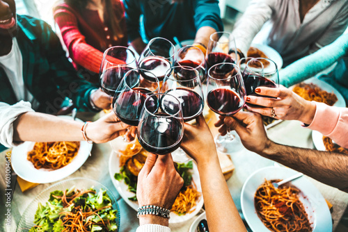 Happy friends toasting red wine glasses at diner party - Group of people having lunch break at bar restaurant - Life style concept with guys and girls hanging out together - Food and beverage