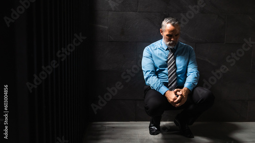 Portrait senior man stressed sad and tired from over working sitting on floor and dark background. Overworked and worried. CEO business company