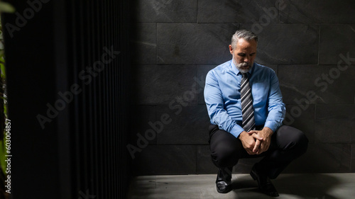 Portrait senior man stressed sad and tired from over working  sitting on floor and dark background. Overworked and worried. CEO business company © NVB Stocker