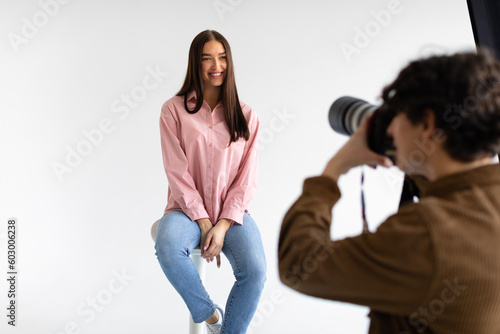 Creating captivating portraits. Photographer taking photos of young european lady, having photoshoot on white background photo