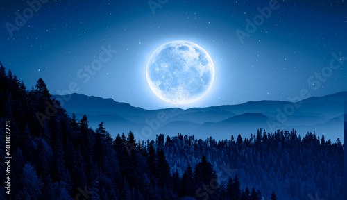 Beautiful landscape with blue misty silhouettes of mountains against super blue moon 