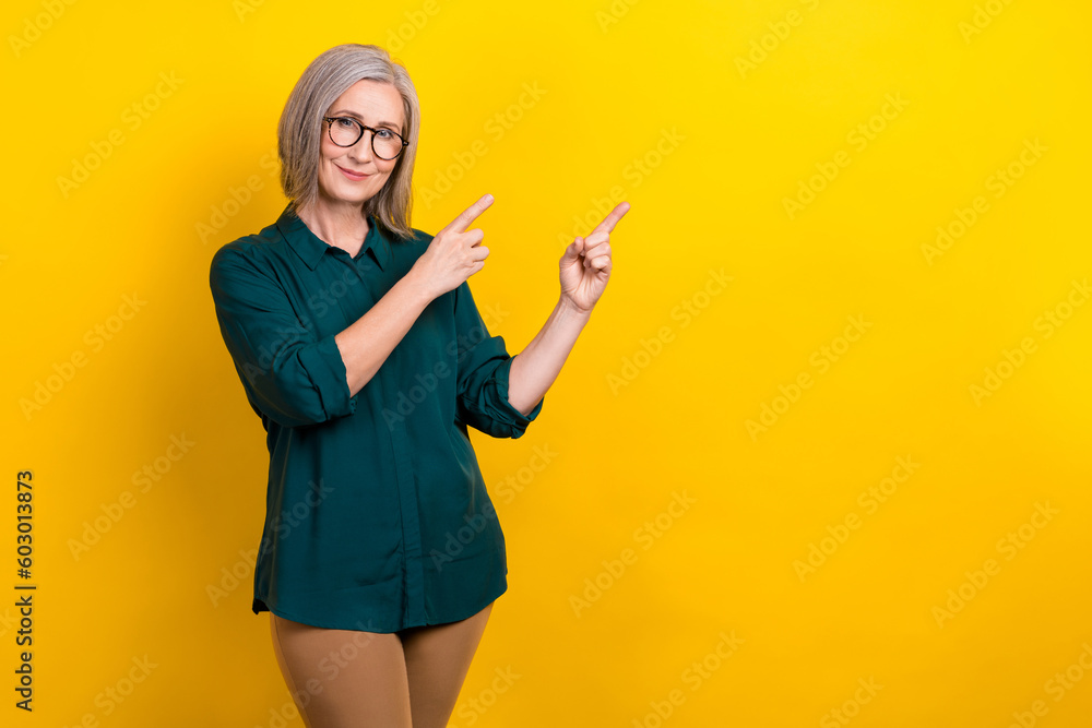 Photo of trader promoter aged lady pointing empty space advertising shopping sale isolated vivid color background Photo of trader promoter aged lady pointing empty space advertising shopping sale isolated vivid color background