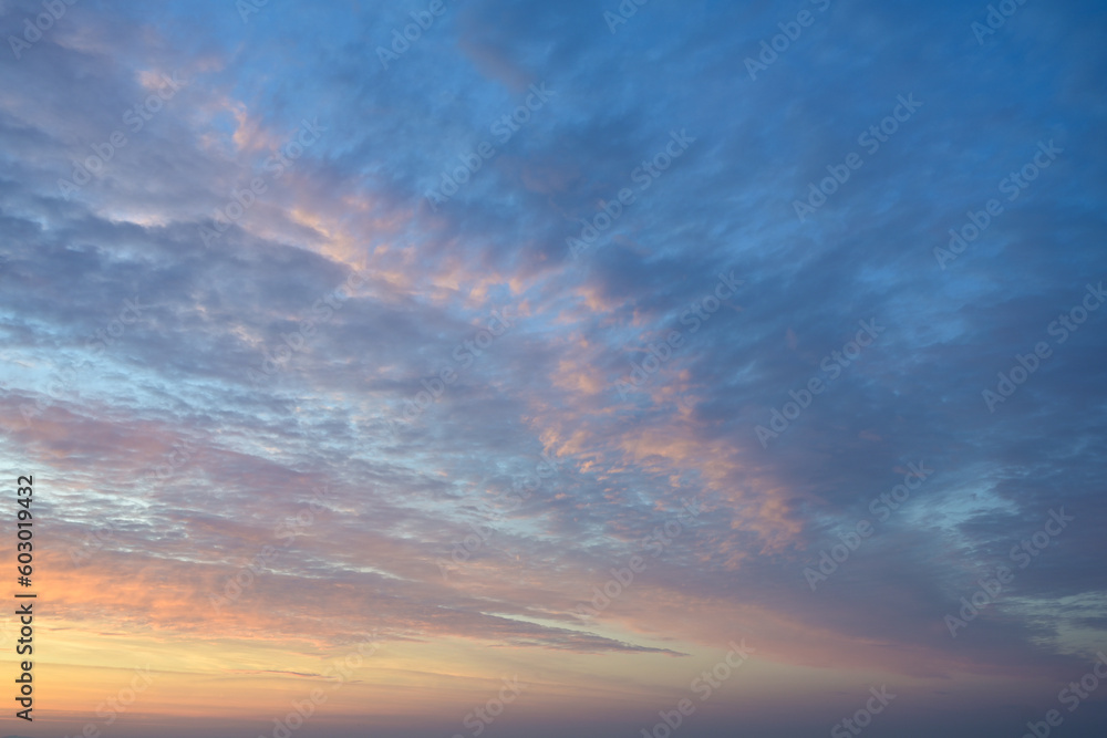Sunrise or sunset sky with light clouds in orange, pink and blue, natural romantic background texture, weather and climate concept, full frame, copy space